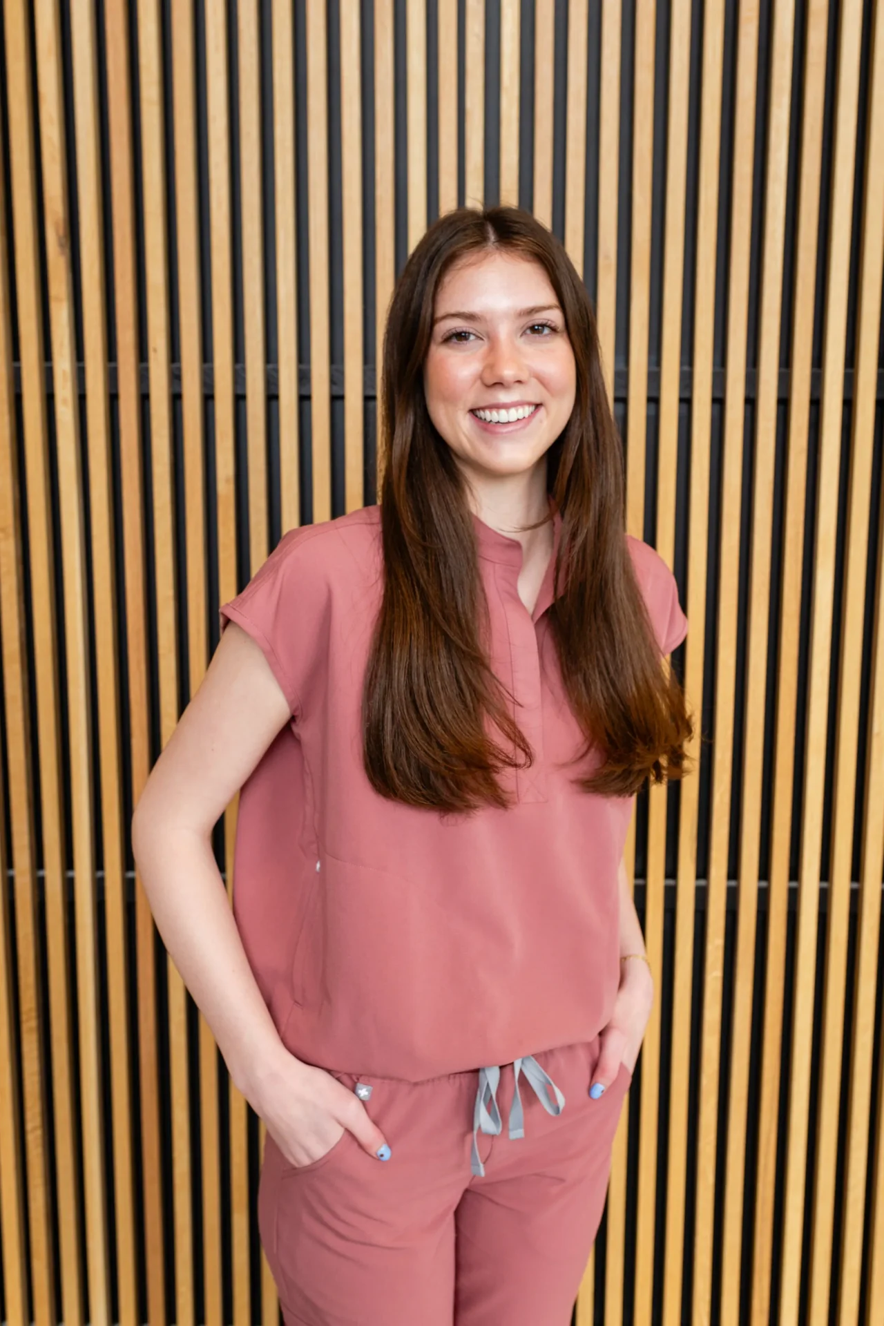 A woman standing in front of a wooden wall.