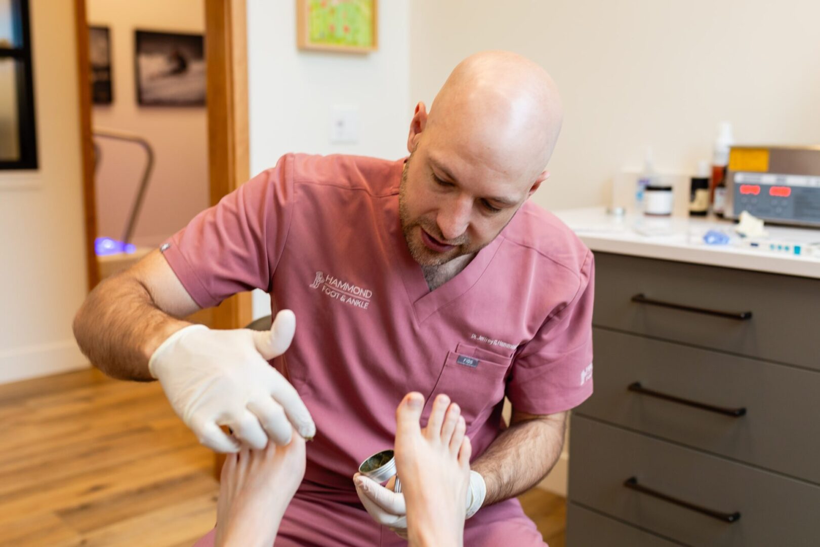 A man in pink shirt getting his foot examined.