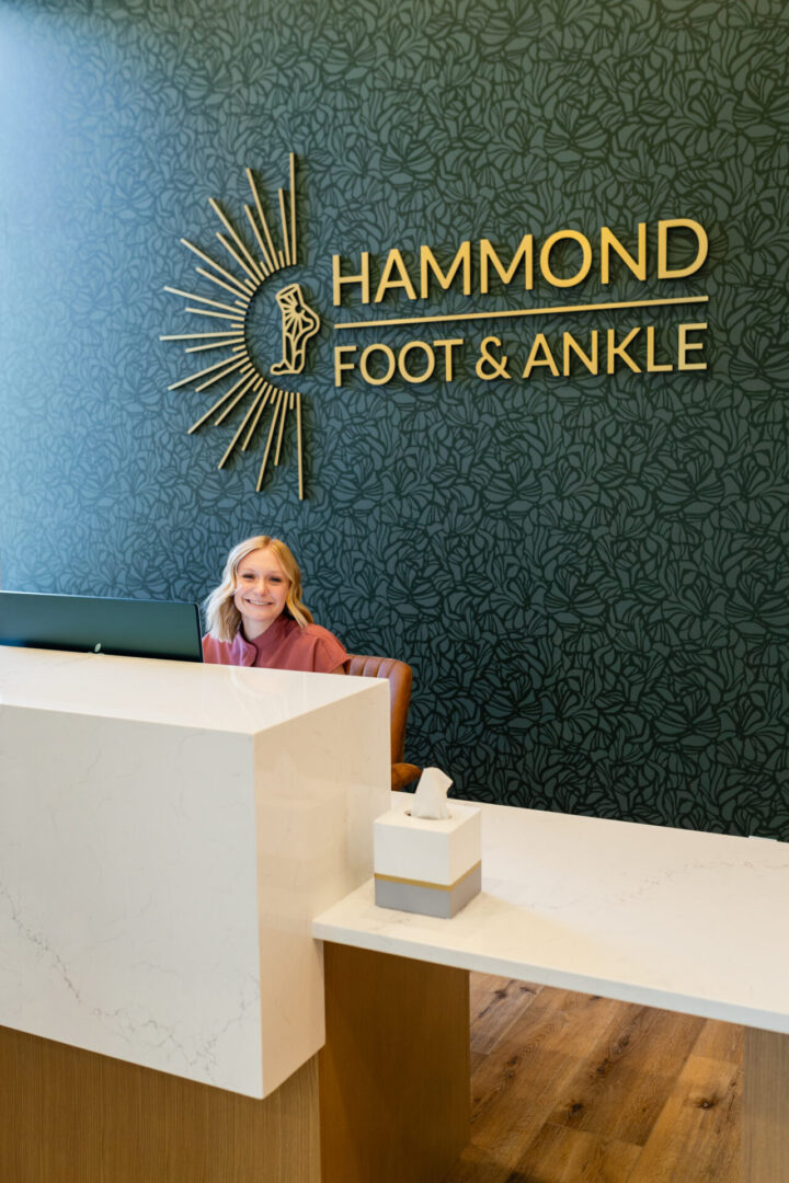 A woman sitting at the reception desk of a foot and ankle clinic.