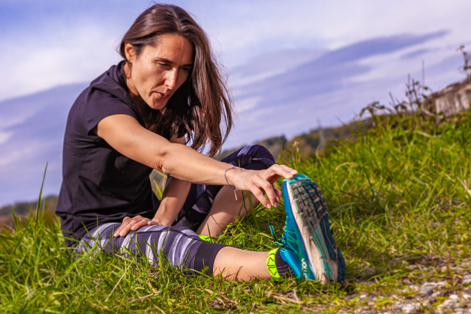 A woman stretching her legs on the grass.